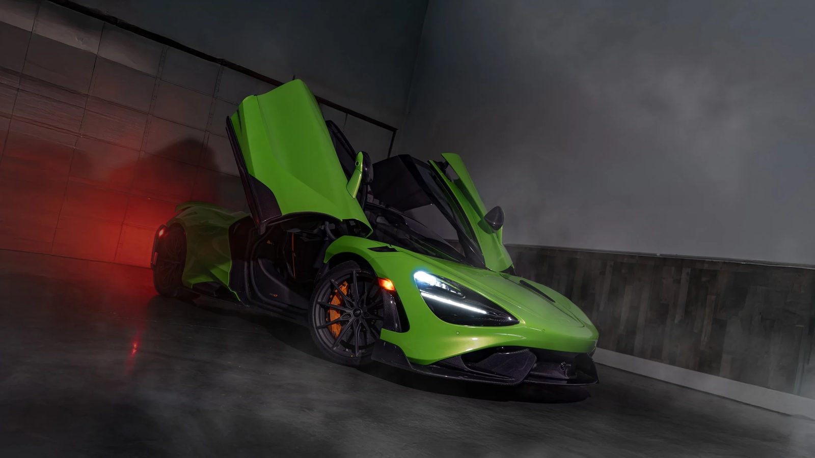 Green McLaren with doors raised, lit in a studio